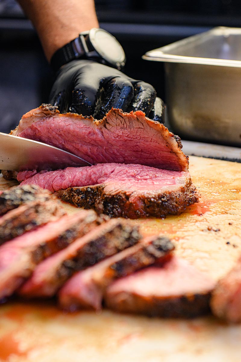 tri tip meat being cut on a cutting board